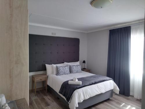 1 dormitorio con 1 cama grande y cabecero grande en Blue Owl Guest House, en Mossel Bay