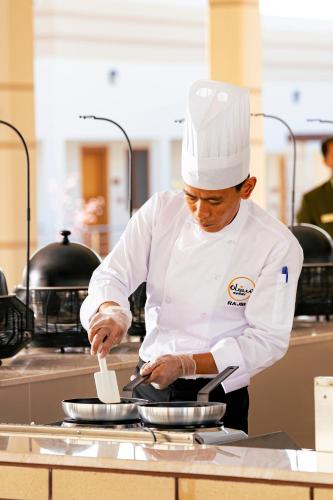 a chef standing in a kitchen preparing food at Damask Resort in Jabal Al Akhdar
