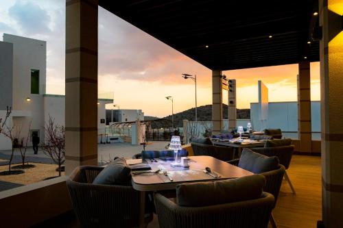 um restaurante com mesas e cadeiras com o pôr-do-sol ao fundo em Damask Resort em Jabal Al Akhdar