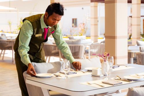 a man is setting a table in a restaurant at Damask Resort in Jabal Al Akhdar