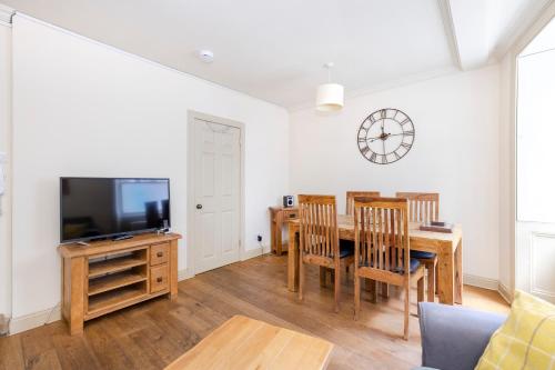 a dining room with a table and a tv at ALTIDO Charming 2-bed house with Courtyard in Edinburgh