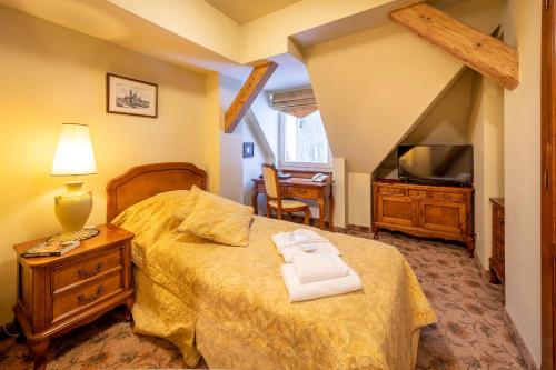 a bedroom with a bed and a tv and a table at Willa Barbara - ProHarmonia in Lądek-Zdrój