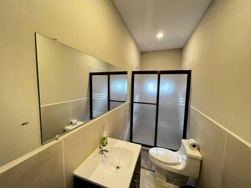 a bathroom with a toilet and a sink and a mirror at Beachfront Flat Brickell@LaCosta in El Zapote