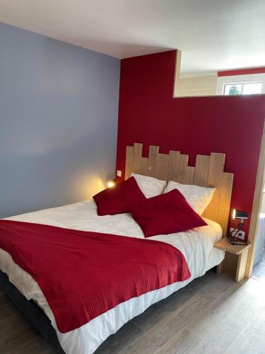 une chambre avec un grand lit avec un mur rouge dans l'établissement Au P'ti Parc de Madon, à Candé-sur-Beuvron