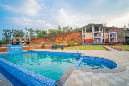 una piscina en un patio con una casa al fondo en Vrindavan Resort, en Mahabaleshwar