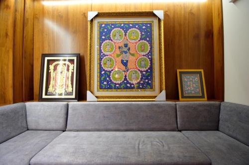 - un canapé dans une chambre avec deux photos sur le mur dans l'établissement The Sky Imperial Hotel Sugam - 10 Meters from Shrinathji Temple, à Nathdwara