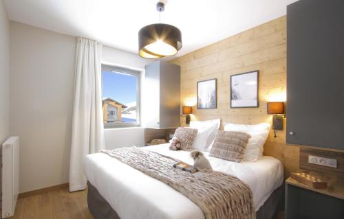 - une chambre avec un grand lit blanc et une fenêtre dans l'établissement Appart'Hôtel Prestige Odalys L'Eclose, à L'Alpe-d'Huez