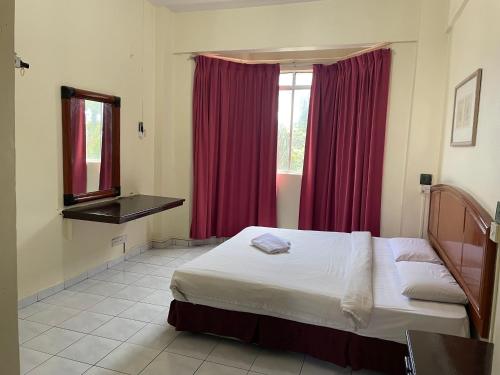 a bedroom with a bed and a window with red curtains at KUHARA COURT APARTMENT SUITE in Tawau