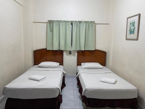 two beds in a small room with a window at KUHARA COURT APARTMENT SUITE in Tawau