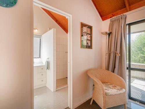 a bathroom with a shower and a chair at Beach Road Beauty - Pauanui Holiday Home in Pauanui