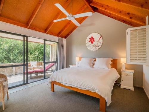 a bedroom with a large bed with a ceiling fan at Beach Road Beauty - Pauanui Holiday Home in Pauanui