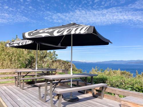 two picnic tables and an umbrella on a deck at 柏島ヴィレッジ in Otsuki