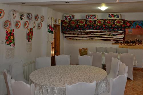 Zimmer mit einem Tisch, Stühlen und Platten an der Wand in der Unterkunft Pensiunea Teodora Teleptean in Vadu Izei