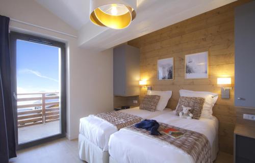1 dormitorio con 2 camas y ventana grande en Résidence Prestige Odalys l'Éclose en L'Alpe-d'Huez