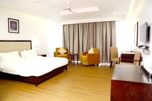 a hotel room with a bed and a desk and chairs at Triguna Clarks Inn Kurnool in Kurnool