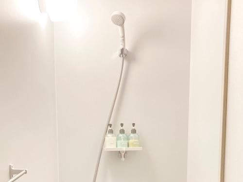 einem Duschkopf und zwei Flaschen auf einem Regal im Bad in der Unterkunft 柏島ヴィレッジ in Otsuki