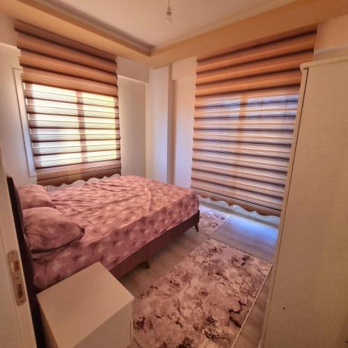 a bedroom with a bed and a window with blinds at Сдаётся квартира с мебелью и техникой 1+1 in Erdemli