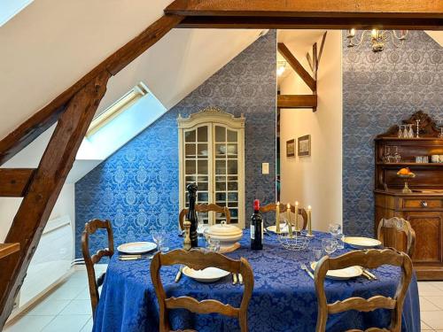 une salle à manger avec une table, des chaises et un mur bleu dans l'établissement La Souveraine - Cottage - Château Le Bas Bleu, à Quesnoy-le-Montant