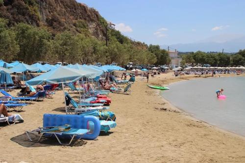 a group of people on a beach with chairs and umbrellas at Kalithea Studio Aptera in Megála Khoráfia