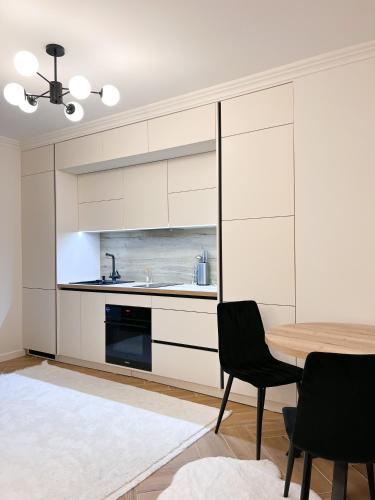 a kitchen with white cabinets and a table and chairs at RentHouse Apartments Neoclassic in Chişinău