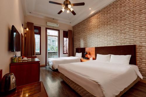 a bedroom with two beds and a brick wall at Super OYO Capital O 1173 Le Grand Hanoi Hotel - The Ruby in Hanoi