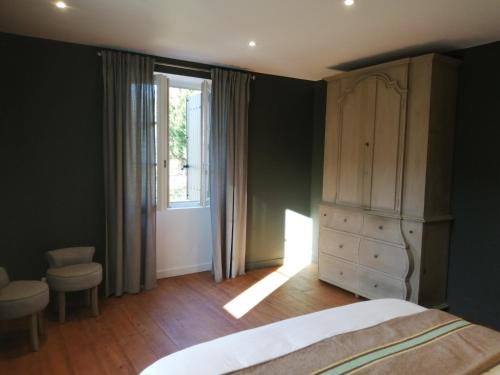 a bedroom with a bed and a dresser and a window at Bedat Coté jardin in Labatut