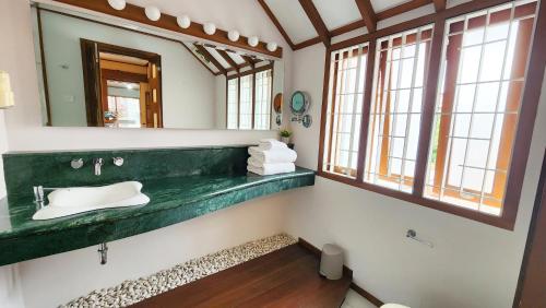 baño con lavabo verde y espejo en Japanese Style Villa at Dago Bandung 4BR Soo Maison, en Bandung