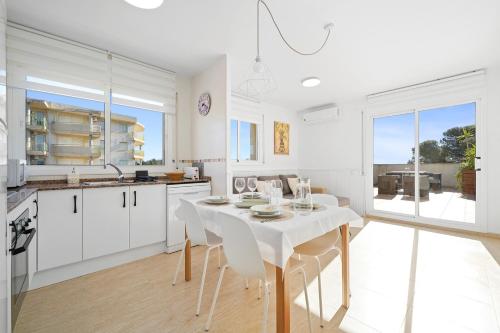 a white kitchen with a white table and chairs at Hauzify I Apartament Mediterrani in Miami Platja