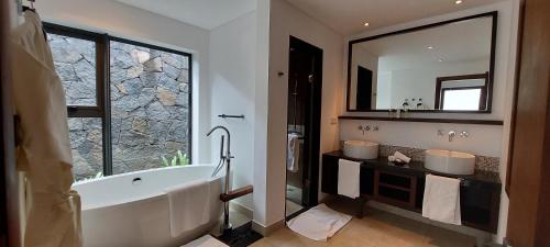 a bathroom with a tub and two sinks and a mirror at Villa Ventura in Bel Ombre