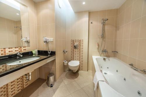 a bathroom with a tub and a toilet and a sink at Qubus Hotel Kielce in Kielce