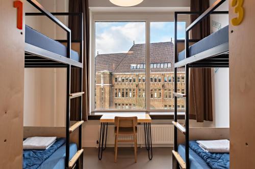 a room with bunk beds and a table and a window at Stayokay Hostel Utrecht Centrum in Utrecht