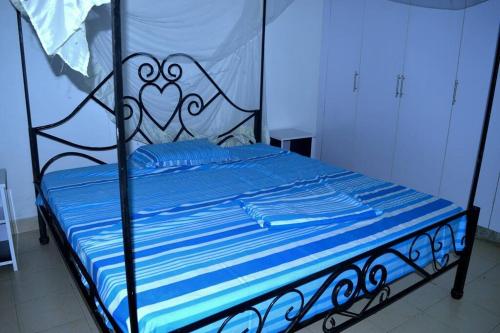 a bed with blue sheets and a black and white bed frame at Bujumbura Sweet Home - Maison bien équipée avec voiture gratuite in Bujumbura