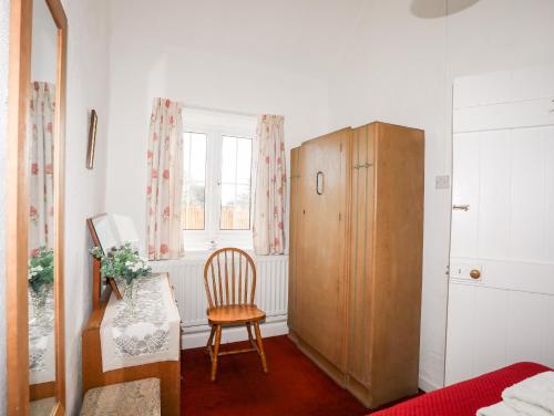 a bedroom with a chair and a wooden cabinet at Ty Hir in Llangoed