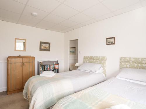 two beds in a room with white walls at Ty Hir in Llangoed