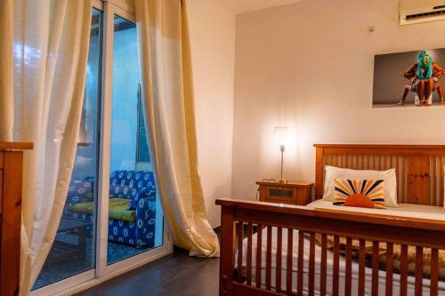 a room with a crib and a chair and a window at Casa Mara Dakar in Dakar