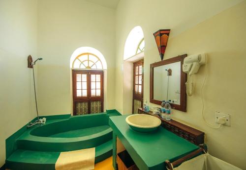 baño con bañera verde y lavamanos en The Swahili House en Zanzíbar