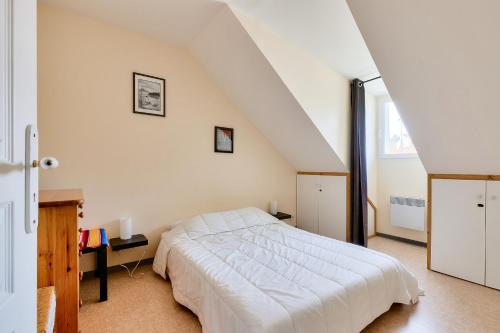 a bedroom with a white bed in a attic at À deux pas de la plage, jolie maison pour 4 in Notre-Dame-de-Monts