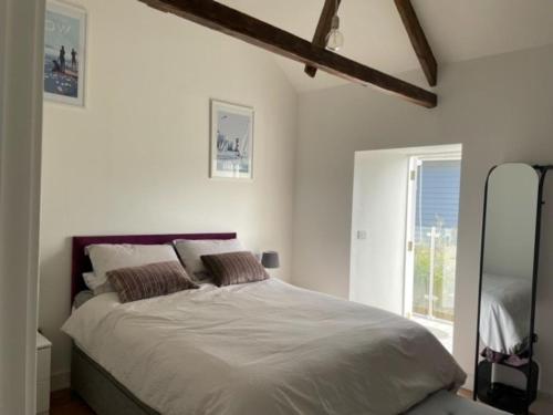 a bedroom with a bed with white sheets and a window at The Bakery Flat, Frogmore in Kingsbridge