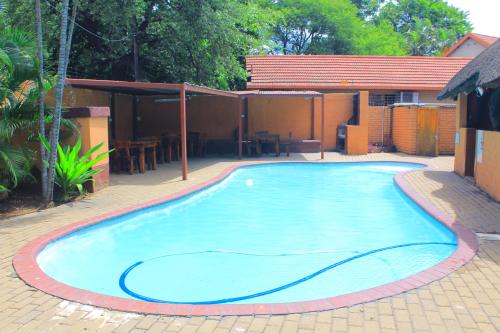 a large blue swimming pool in a yard at Butterflytree Guest House in Phalaborwa