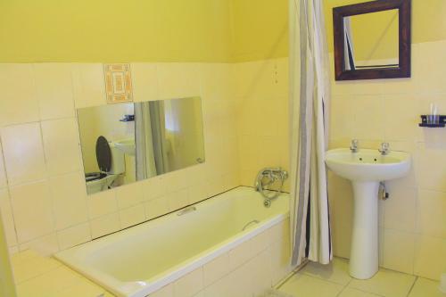 La salle de bains est pourvue d'un lavabo et d'une baignoire. dans l'établissement Butterflytree Guest House, à Phalaborwa