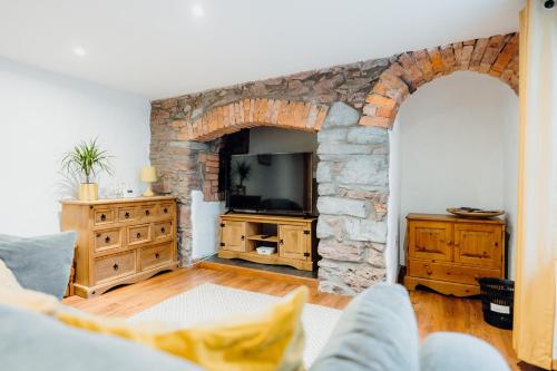 テンビーにあるThe Bakehouse - Cosy conversion with Outdoor Saunaの石壁のリビングルーム(テレビ付)