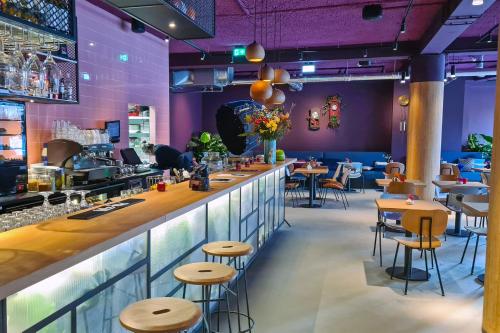 a bar in a restaurant with purple walls and stools at Stayokay Hostel Utrecht Centrum in Utrecht