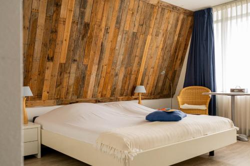 een slaapkamer met een bed met een houten muur bij Hotel Kijkduin in Domburg