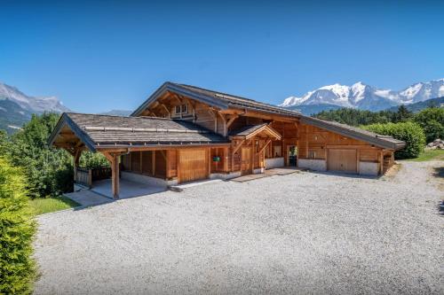 a house with a large driveway in front of mountains at Chalet Les Vosnes - OVO Network in Domancy