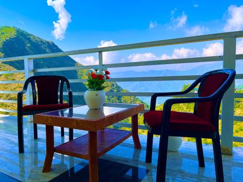 two chairs and a table with a vase of flowers on a balcony at The Kempty Fall Resort, Mussoorie in Mussoorie