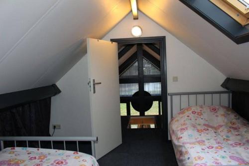 a attic room with a bed and a window at Ottenskamp4 in Siebengewald