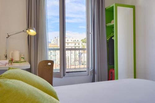 a bedroom with a bed and a large window at Campanile Hotel Nice Centre Acropolis in Nice