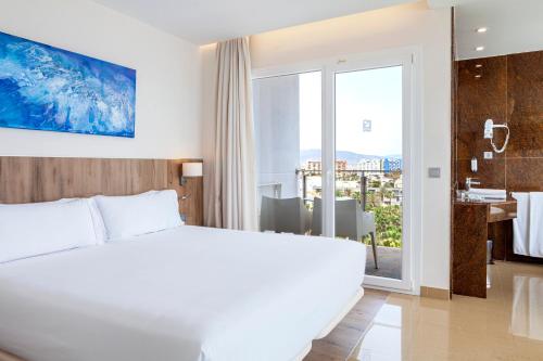 a bedroom with a large white bed and a bathroom at Playasol in Roquetas de Mar