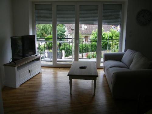 ein Wohnzimmer mit einem Sofa, einem TV und einem Tisch in der Unterkunft Appartement Cransac 2 in Cransac