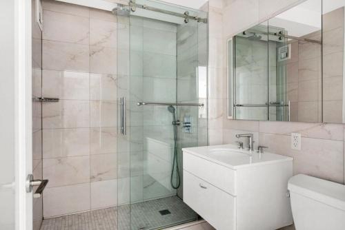 a bathroom with a shower and a sink and a mirror at Midtown W 1BR w Gym Doorman nr Times Sq NYC-692 in New York
